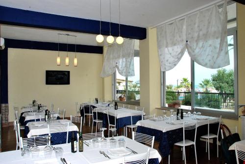 a dining room with white tables and chairs and windows at Tourist Residence in San Benedetto del Tronto