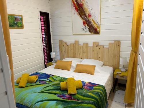 a bedroom with a bed with yellow pillows at L'escale Tropicale in Sainte-Anne