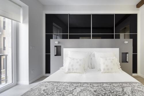 1 dormitorio con 1 cama blanca grande con almohadas blancas en Zurriola Zinema by FeelFree Rentals, en San Sebastián