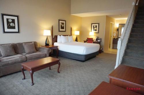 a hotel room with a bed and a couch at Ramada by Wyndham Kelowna Hotel & Conference Center in Kelowna