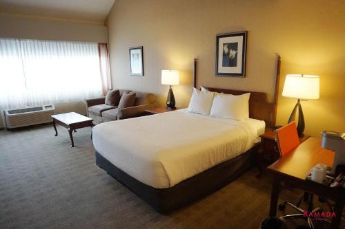 a hotel room with a large bed and a couch at Ramada by Wyndham Kelowna Hotel & Conference Center in Kelowna
