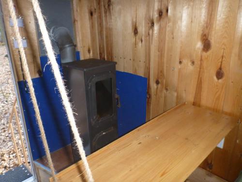 a stove in a wooden room with a wooden table at Bauwagen Schorfheide supergut isoliert ganzjährig nutzbar in Joachimsthal