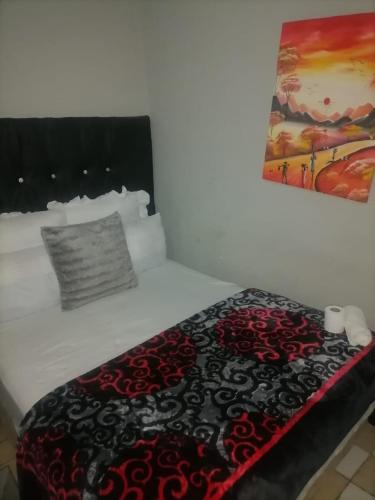 a bed with a black and red blanket on it at Guest room florida in Roodepoort