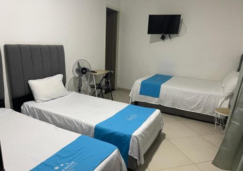 a room with two beds and a flat screen tv at Hotel House in Medellín