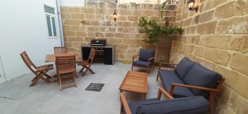 a living room with chairs and a table and a brick wall at DAHLIA APARTMENT Paola in Paola