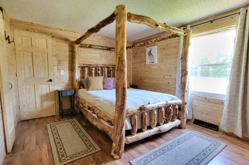 Dormitorio con cama con dosel en una cabaña de madera en Close to Munising, Pictured Rocks, ORV access, en Shingleton