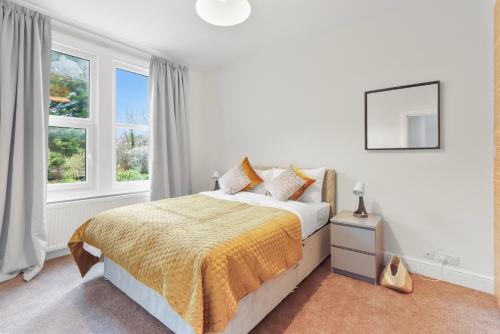 a white bedroom with a bed and a window at Windsor House near the Park in Hendon