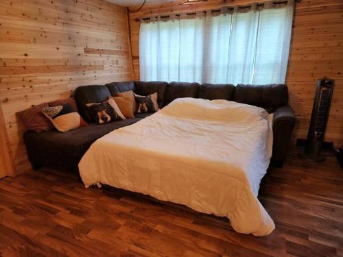 a black leather couch in a room with a bed at Close to Munising, Pictured Rocks, ORV access in Shingleton
