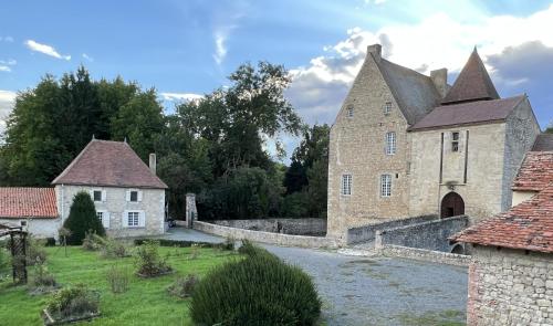 - un grand bâtiment en pierre avec une rivière en face dans l'établissement Le Château de la Mothe de Vicq, à Vicq