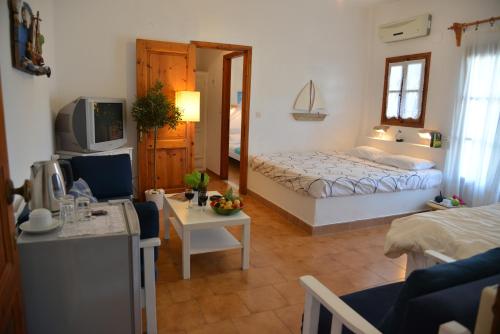 a living room with a bed and a room with a table at Anofli Suites in Skopelos Town