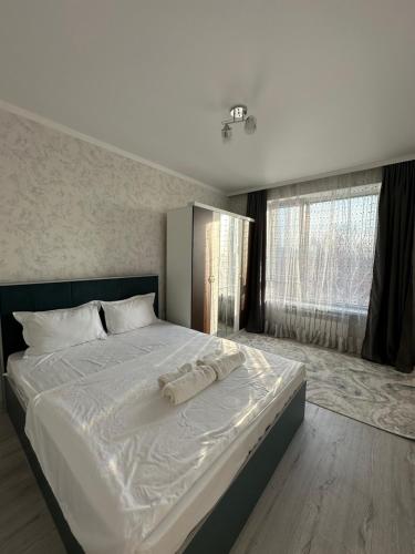 1 dormitorio con 1 cama grande con sábanas blancas en ЖК Ashyq Tobe, en Almaty