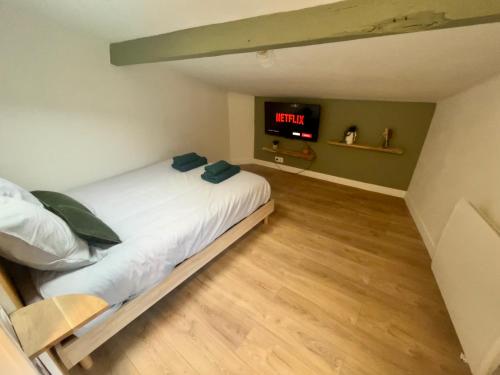 - une chambre avec un lit et une télévision murale dans l'établissement Sous les toits du parvis, à Niort