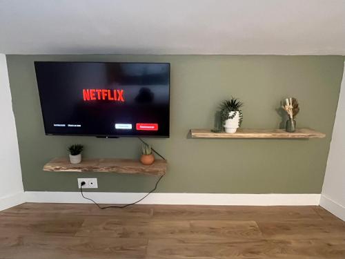 un salon avec une télévision sur un mur dans l'établissement Sous les toits du parvis, à Niort