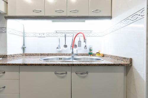 eine Küche mit einem Waschbecken und weißen Schränken in der Unterkunft David's House in Barcelona