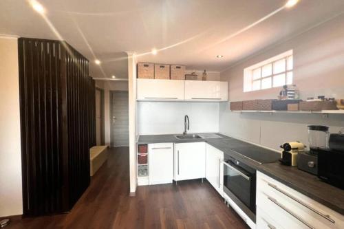uma cozinha com armários brancos e um balcão preto em Cosy T2 at 10 minutes from the sea! em Mandelieu-la-Napoule