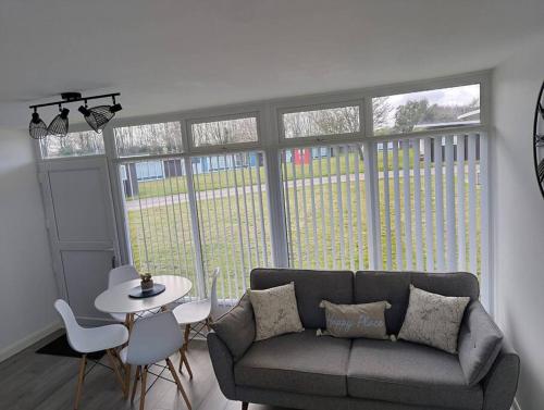 a living room with a couch and a table at Chalet in Stalham in Stalham