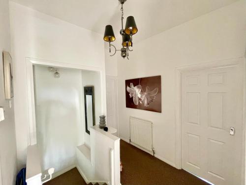 un pasillo con una puerta blanca y una lámpara de araña en Clydfan, en Holyhead