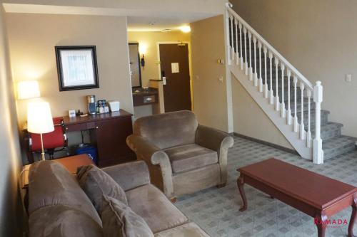a living room with a couch and a chair and stairs at Ramada by Wyndham Kelowna Hotel & Conference Center in Kelowna