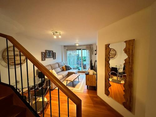 a living room with a couch and a staircase at Coqueto Dúplex con dos terrazas y piscina cerca de la playa de la Virgen del Mar in Santander