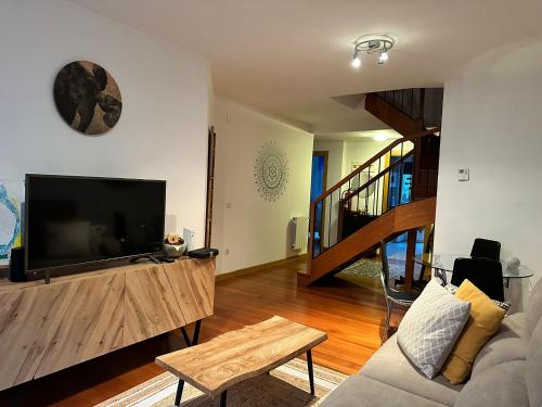 a living room with a flat screen tv and a couch at Coqueto Dúplex con dos terrazas y piscina cerca de la playa de la Virgen del Mar in Santander