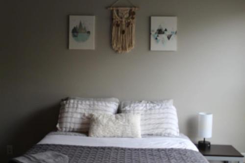 um quarto com uma cama com lençóis brancos e fotografias na parede em Spacious 2BR Suite Plus Patio Near Iowa State em Ames