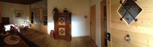 a living room with a wooden floor and a room with a grandfather clock at Platzerhof in Monguelfo