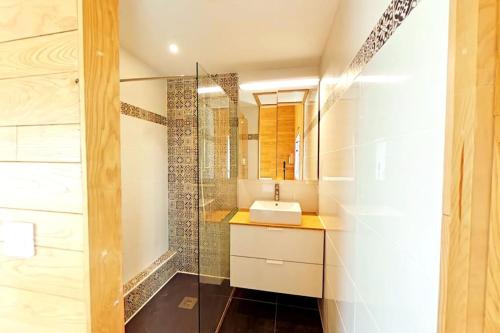 a bathroom with a sink and a glass shower at Maison de vacances, chaleureuse, avec sauna in Santec