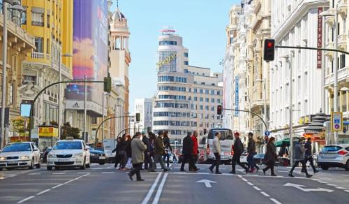 un grupo de personas cruzando una concurrida calle de la ciudad en Punta me Rooms in Madrid Downtown, en Madrid