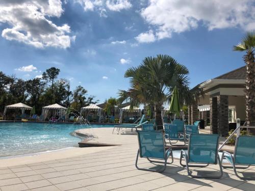 uma piscina com cadeiras azuis e palmeiras num resort em Maggie's Cozy Corner em Wimauma