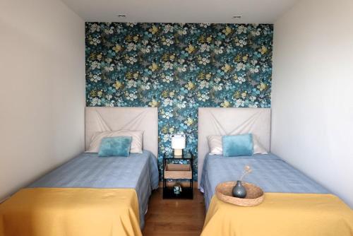 um quarto com 2 camas e um papel de parede floral em Vitoria-Gasteiz magnífica casa em Vitoria-Gasteiz