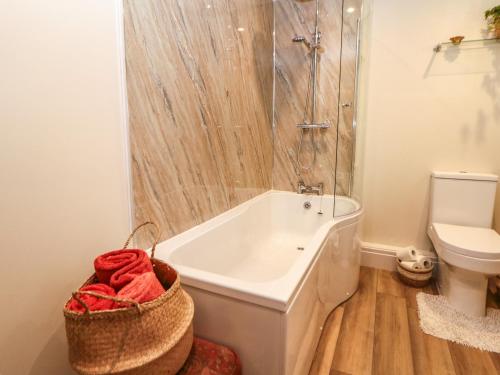 a white bathroom with a tub and a toilet at Shippon Cottage in Castleton