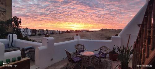 a sunset on a balcony with a table and chairs at The Green House in Hurghada