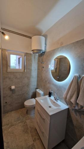 uma casa de banho com um WC, um lavatório e um espelho. em Dobrić em Kaštel Štafilić