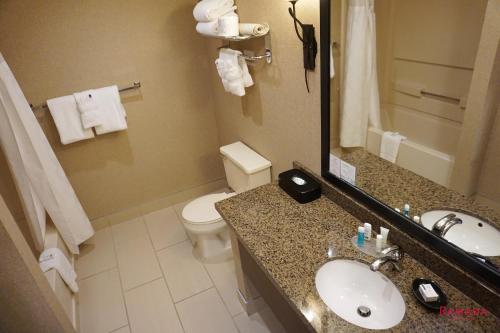 a bathroom with a sink and a toilet and a mirror at Ramada by Wyndham Kelowna Hotel & Conference Center in Kelowna