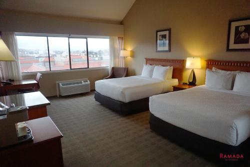 a hotel room with two beds and a window at Ramada by Wyndham Kelowna Hotel & Conference Center in Kelowna