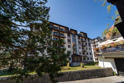 a tall building with a tree in front of it at Adoro Titova Vila in Zlatibor