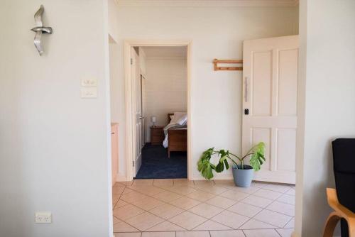 a hallway with a potted plant and a bedroom at Charming Cottage, 7 mins walk to the beach and golf! in Torquay