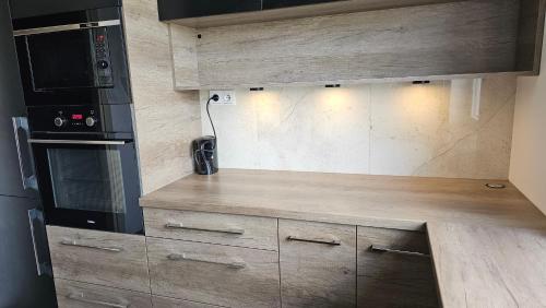 a kitchen with wooden cabinets and a microwave at Wygodny apartament in Łomża