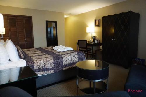 a hotel room with a bed and a table at Ramada by Wyndham Kelowna Hotel & Conference Center in Kelowna