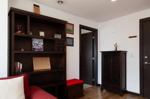 a living room with a book shelf and a red couch at Olympus Apartments in Quito