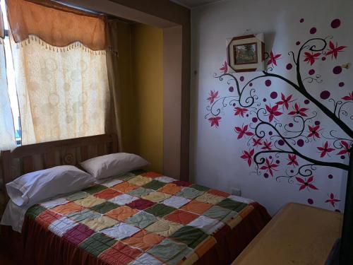 a bedroom with a bed with a tree mural on the wall at Hospedaje Luciano in Ayacucho