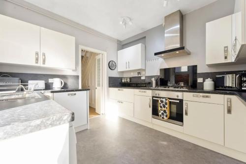 a white kitchen with white cabinets and appliances at The Capstone Retreat - Beautiful Detached Family Home By Coastline Retreats, Arcade Machine, Parking, BBQ in Bournemouth