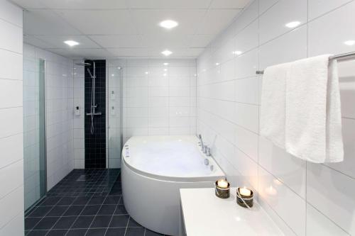 La salle de bains blanche est pourvue d'une baignoire et d'un lavabo. dans l'établissement Scandic Triangeln, à Malmö