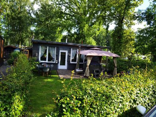 una piccola casa blu con un ombrello in cortile di Chalet met hottub a Lanaken