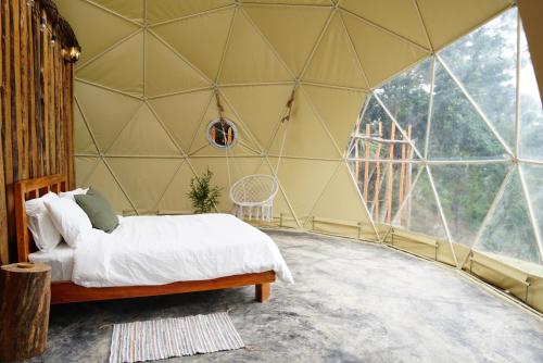 a bedroom with a bed in a room with a large window at NOMAD Domes Sky Watching at Jarabacoa in Jarabacoa