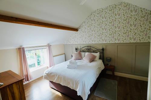 a bedroom with a bed with white sheets and pink pillows at Oak Tree Barn in Pickering