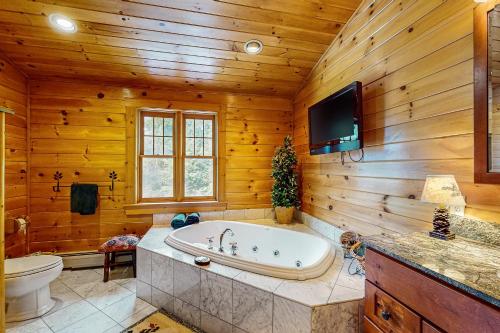 baño con bañera y TV en una pared de madera en Sunday River Ridge, en Newry