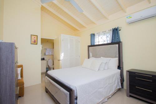 a bedroom with a bed with white sheets and a bathroom at Ocho Rios Drax Hall Manor 3 Bed Getaway in Mammee Bay