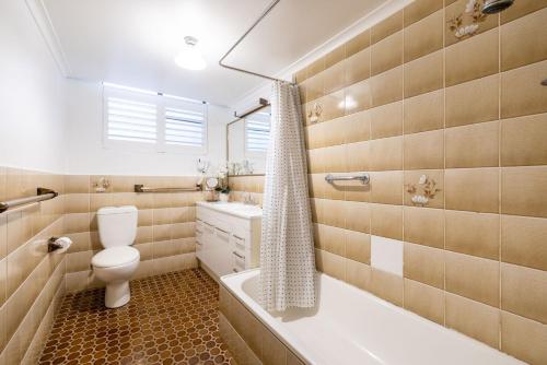 Un baño con inodoro, bañera y lavabo. en 14 The Dunes large unit with pool tennis court and directly across from Fingal beach, en Fingal Bay