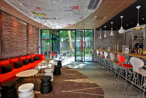 ein Restaurant mit roten Sitzgelegenheiten und Tischen und eine Bar in der Unterkunft Ibis Muenchen City Ost in München
